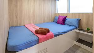 a small room with a bed with blue and pink sheets at Ocean Odyssey in Na Jomtien