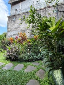 a garden in front of a stone building at Kope House Ubud in Ubud