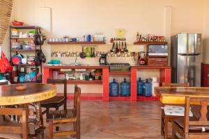 a restaurant with tables and a kitchen with a refrigerator at Casa San Jerónimo in Puerto Escondido