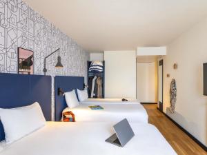 a hotel room with two beds and a wall at ibis Dunkerque in Dunkerque