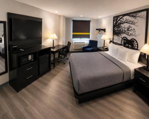 a hotel room with a bed and a desk and a television at Super 8 by Wyndham Lexington Park/California Area in California