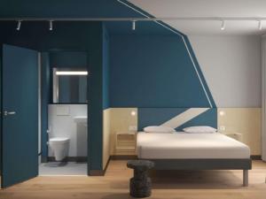 a bedroom with a bed and a blue wall at IBIS BUDGET GUINGAMP in Ploumagoar +5 photos