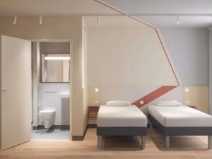 a room with two beds and a bathroom at IBIS BUDGET GUINGAMP in Ploumagoar