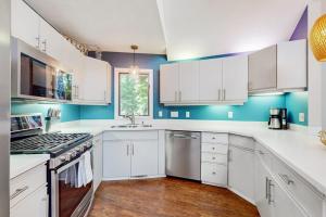 a white kitchen with blue walls and white cabinets at The Tree House in New Buffalo +19 photos