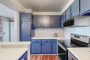 a blue kitchen with white counters and blue cabinets at Ship Watch 15 in Glen Arbor