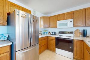 a kitchen with wooden cabinets and a stainless steel refrigerator at Northern Michigan Manistee Magic in Manistee