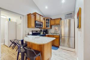 a kitchen with wooden cabinets and a stainless steel refrigerator at Arrowhead Resort - Stylish Retro Escape in Saugatuck