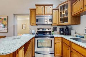 a kitchen with wooden cabinets and a stove top oven at Arrowhead Resort - Stylish Retro Escape in Saugatuck