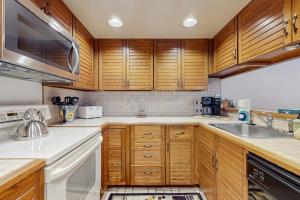 a kitchen with wooden cabinets and a sink at Ski & Tee Boyne Highlands Townhouse in Harbor Springs