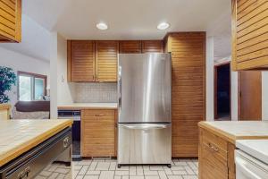 a stainless steel refrigerator in a kitchen with wooden cabinets at Ski & Tee Boyne Highlands Townhouse in Harbor Springs +13 photos