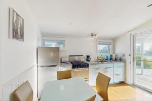 a kitchen with white cabinets and a table with chairs at Bayside Breeze in Truro