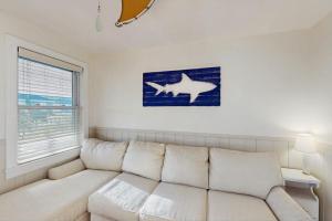 a white couch in a living room with a shark on the wall at Bayside Breeze in Truro