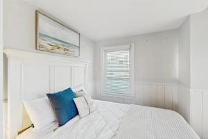 a white bedroom with a white bed with blue pillows at Bayside Breeze in Truro +9 photos