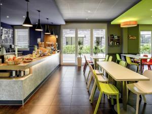a restaurant with green walls and tables and yellow chairs at ibis budget Winterthur in Winterthur