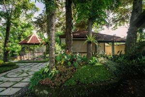 a garden with trees and a building with a pavilion at The Kharma Villas Yogyakarta in Yogyakarta