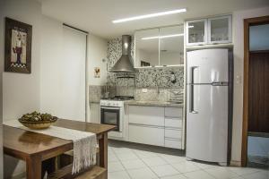 a kitchen with a white refrigerator and a table at Apt. Enseada Praia do Forte in Praia do Forte