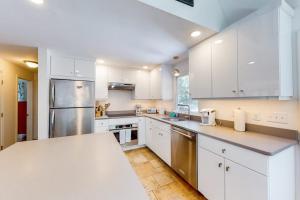a kitchen with white cabinets and stainless steel appliances at Osprey View Villa in Dennis
