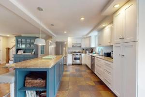 a large kitchen with white cabinets and a blue island at Bumps River Bungalow in Centerville