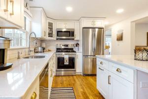 a kitchen with white cabinets and stainless steel appliances at Harbortown Hideaway in Falmouth