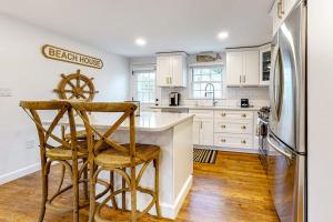 a kitchen with white cabinets and a counter with stools at Harbortown Hideaway in Falmouth