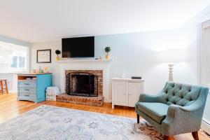 a living room with a chair and a fireplace at Collingwood Cottage in Yarmouth Port