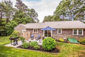 a house with a patio with an umbrella at Collingwood Cottage in Yarmouth Port
