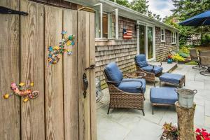 a wooden fence with chairs and an umbrella on a patio at Collingwood Cottage in Yarmouth Port +19 photos