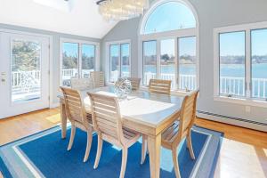 a dining room with a table and chairs and windows at Island Bay Bungalow in Eastham