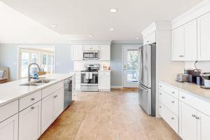 a kitchen with white cabinets and stainless steel appliances at Island Bay Bungalow in Eastham +22 photos