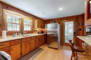 a kitchen with wooden cabinets and a stainless steel refrigerator at Pickerel Cove Cottage in Mashpee +17 photos
