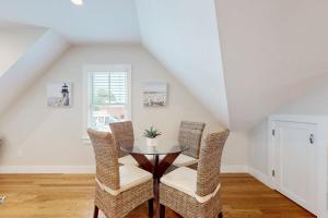 a dining room with a glass table and wicker chairs at Oyster Beach Bungalow in Chatham