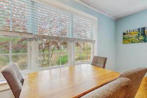a dining room with a wooden table and two windows at Cozy Charming Cottage in Brewster
