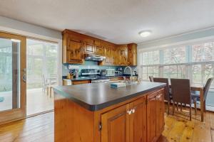 a kitchen with wooden cabinets and a kitchen island with a table at Cozy Charming Cottage in Brewster