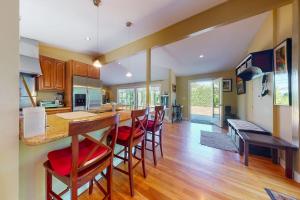 a kitchen with a bar with red cushioned chairs at Yellow Brick Road House in Oak Bluffs