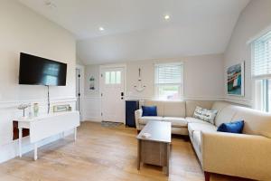 a living room with a couch and a tv at The Quintessential Cape Cottage in Orleans