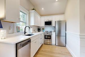 a kitchen with white cabinets and a stainless steel refrigerator at The Quintessential Cape Cottage in Orleans