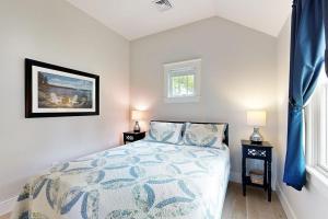 a bedroom with a bed and two tables with lamps at The Quintessential Cape Cottage in Orleans