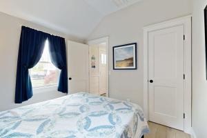 a bedroom with a bed with blue curtains and a window at The Quintessential Cape Cottage in Orleans +11 photos