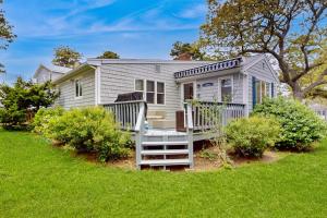 a white tiny house with a porch at Cape Beach Bungalow in Dennis Port