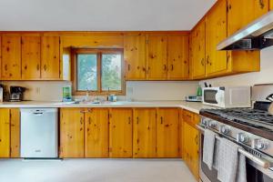 a kitchen with wooden cabinets and a sink and a stove at Cape Beach Bungalow in Dennis Port +10 photos