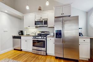 a kitchen with white cabinets and a stainless steel refrigerator at Salty Kisses Unit 20 in Yarmouth +9 photos