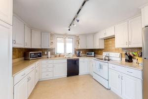 a large white kitchen with white cabinets and appliances at Kalmus Park Retreat in Hyannis