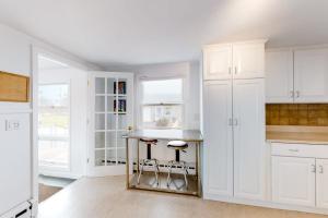 a kitchen with white cabinets and a counter with stools at Kalmus Park Retreat in Hyannis +27 photos