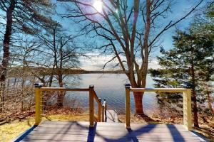 ein Holzsteg, der zu einem See mit einem Baum führt in der Unterkunft Lovells Landing in Cotuit
