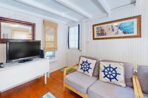a living room with a couch and a flat screen tv at Canary Cottage in Oak Bluffs