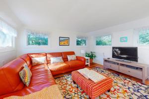 a living room with a leather couch and a flat screen tv at Canary Cottage in Oak Bluffs +20 photos