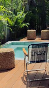 a chair sitting on a deck next to a swimming pool at AWÊ Villa Boutique & Beach Club in Trancoso