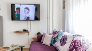 een woonkamer met een paarse bank en een tv aan de muur bij Lake Side Apartments by ZagrebRent in Zagreb