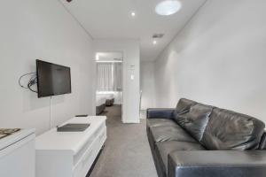 a living room with a couch and a flat screen tv at Mawson Lakes Hotel in Mawson Lakes