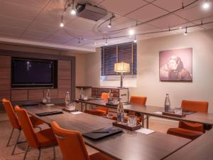 a conference room with tables and chairs and a flat screen tv at Royal Emeraude Hotel Dinard - MGallery Collection in Dinard